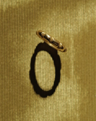 Gold band with raised ridges, casting an oval shadow on gold silk